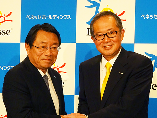 記者会見席上、握手を交わす新社長の安達保氏（写真右）と福原賢一氏